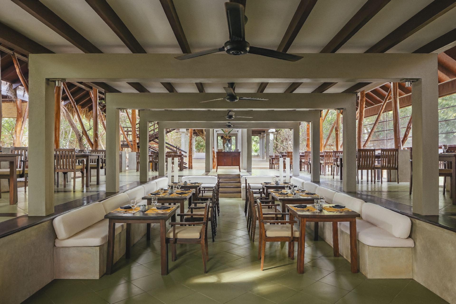 The main restaurant: an open pavilion with laid tables under ceiling fans