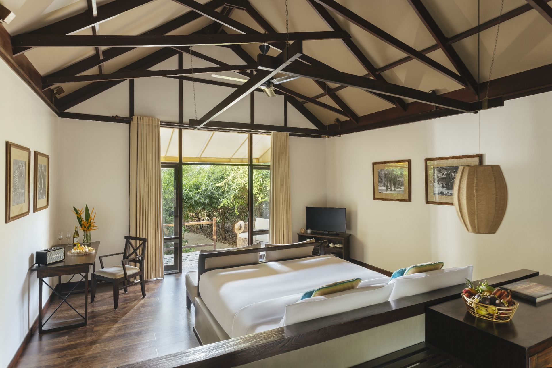 Inside a beach cabin: a low bed, timber roof beams and glass doors to a deck