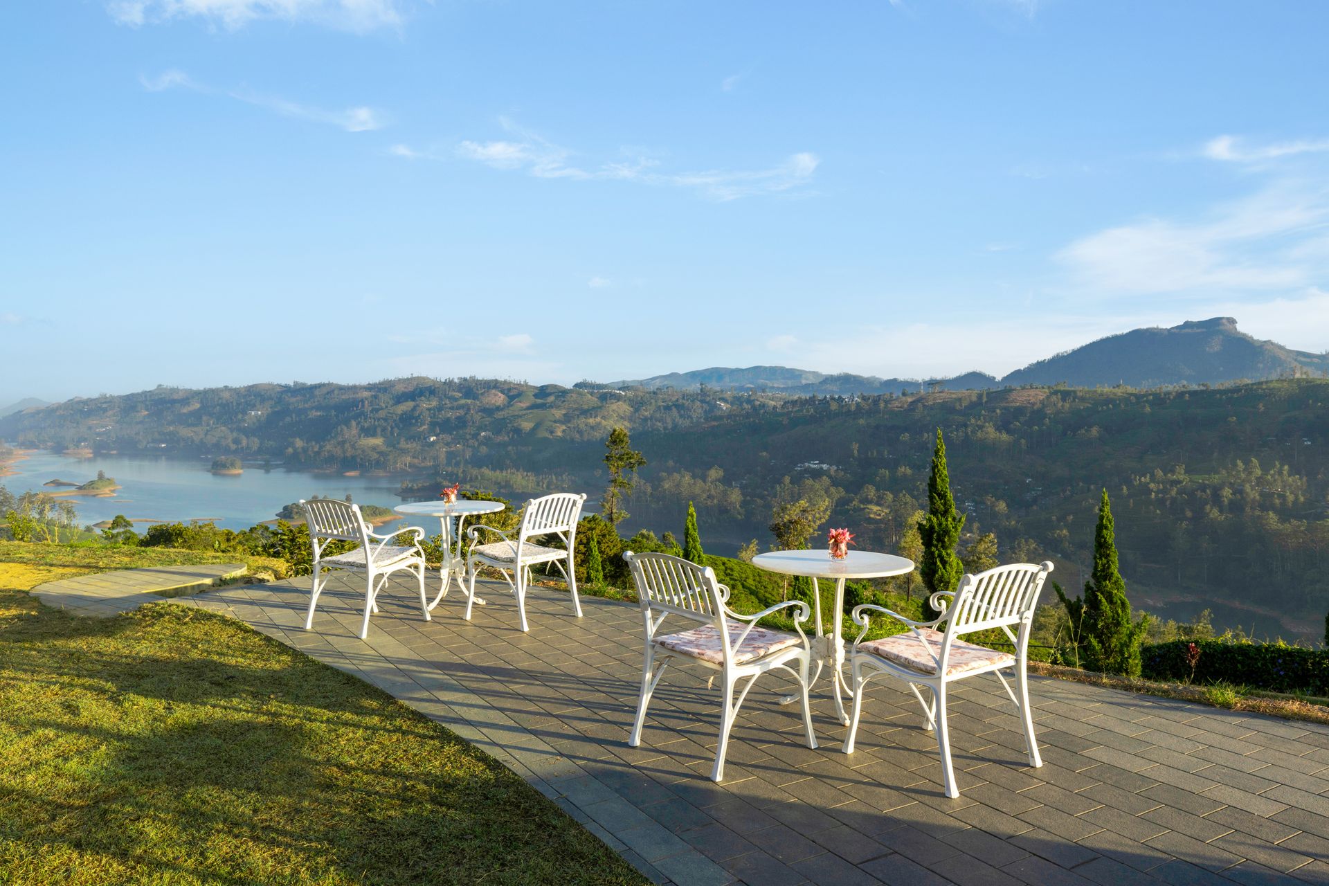 White garden tables on the terrace looking down to the reservoir and a distant peak